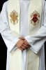 Zbliżenie dwóch haftowanych symboli na stule ecru