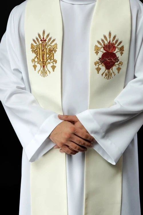 Zbliżenie dwóch haftowanych symboli na stule ecru