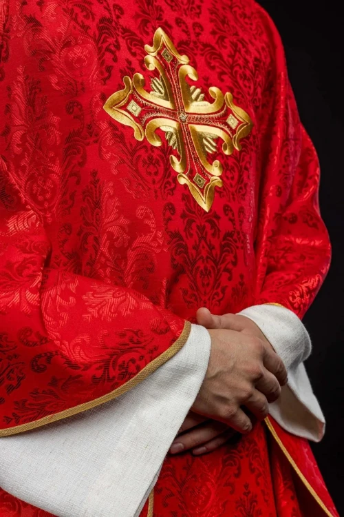 Ornat czerwony z haftowanym krzyżem na wzorzystej tkaninie – detal symbolu