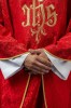Czerwony ornat liturgiczny z haftowanym motywem IHS na ozdobnej tkaninie – detal symbolu