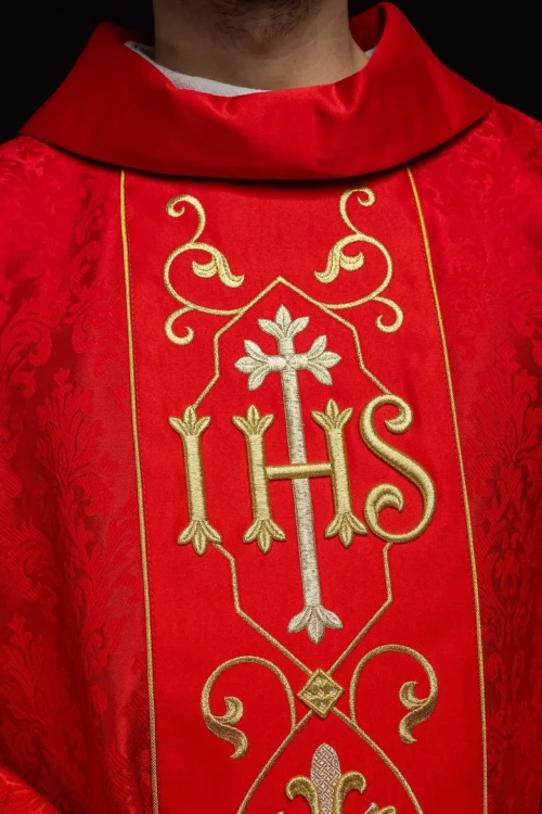 Ornat czerwony z haftem IHS na ozdobnej tkaninie – zbliżenie haftu
