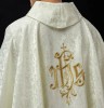 Ornat liturgiczny ecru z haftem IHS na ozdobnej tkaninie – detal symbolu
