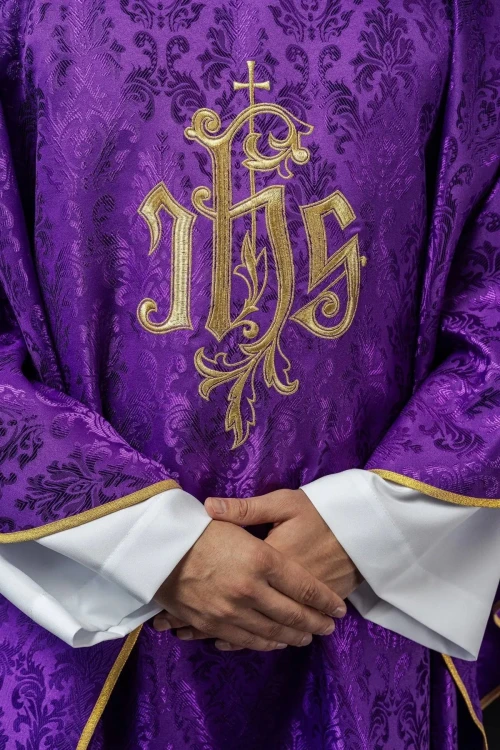 Fioletowy ornat liturgiczny z haftowanym motywem IHS na ozdobnej tkaninie – zbliżenie haftu