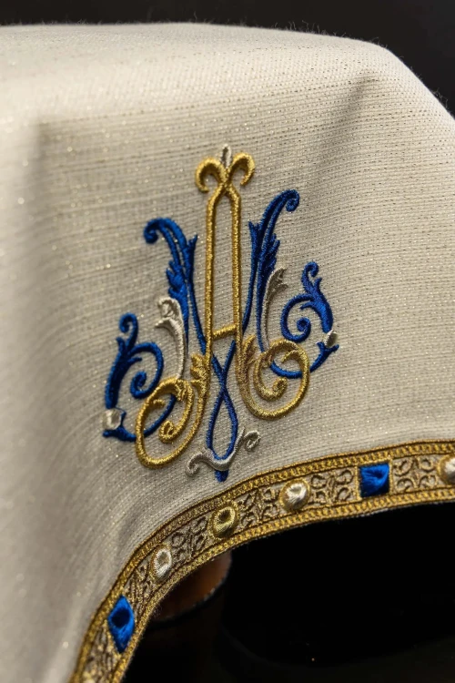 Monogram maryjny i zdobione obrzeże welonu ecru – detal