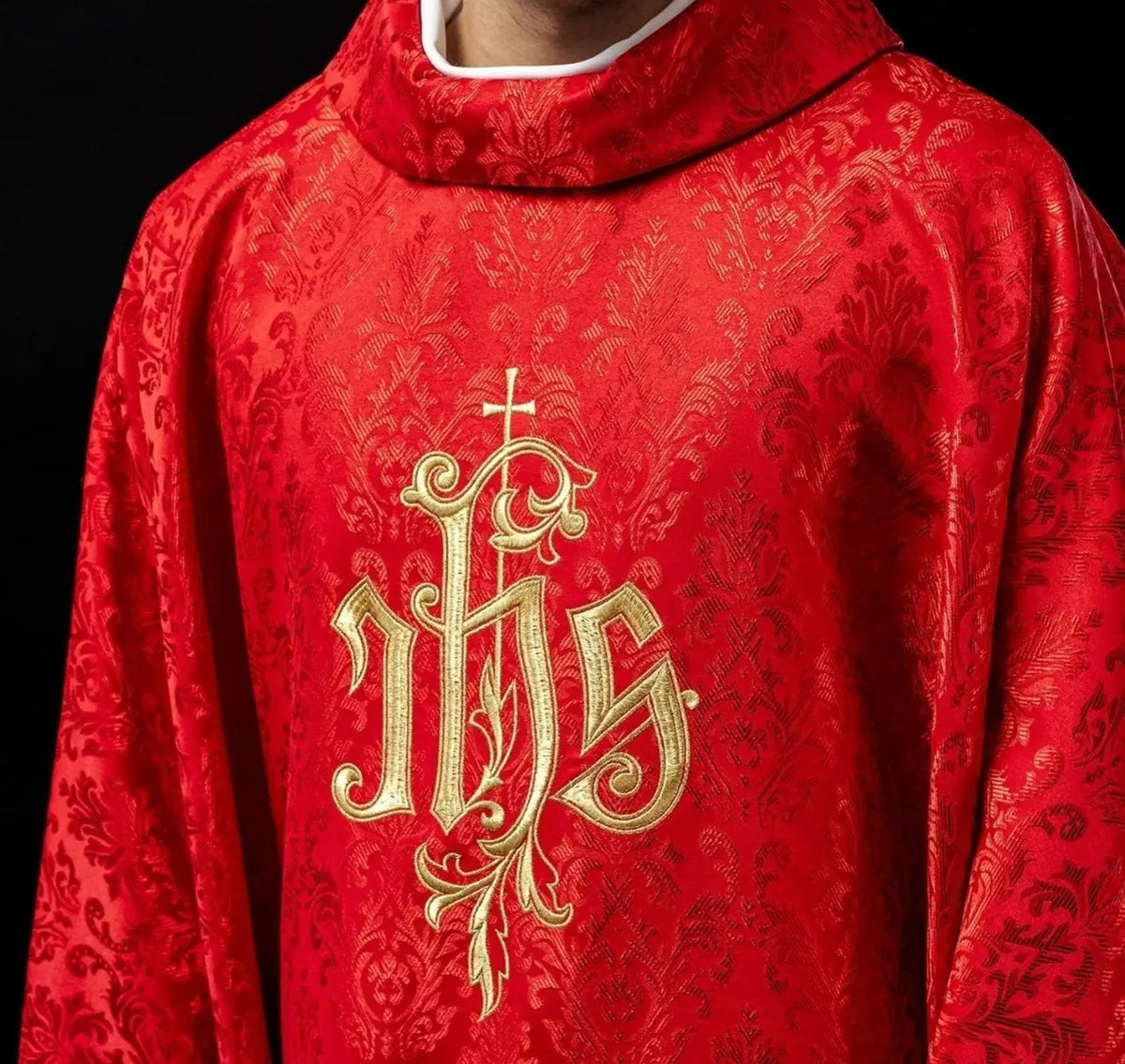 Czerwony ornat liturgiczny z haftowanym motywem IHS na ozdobnej tkaninie